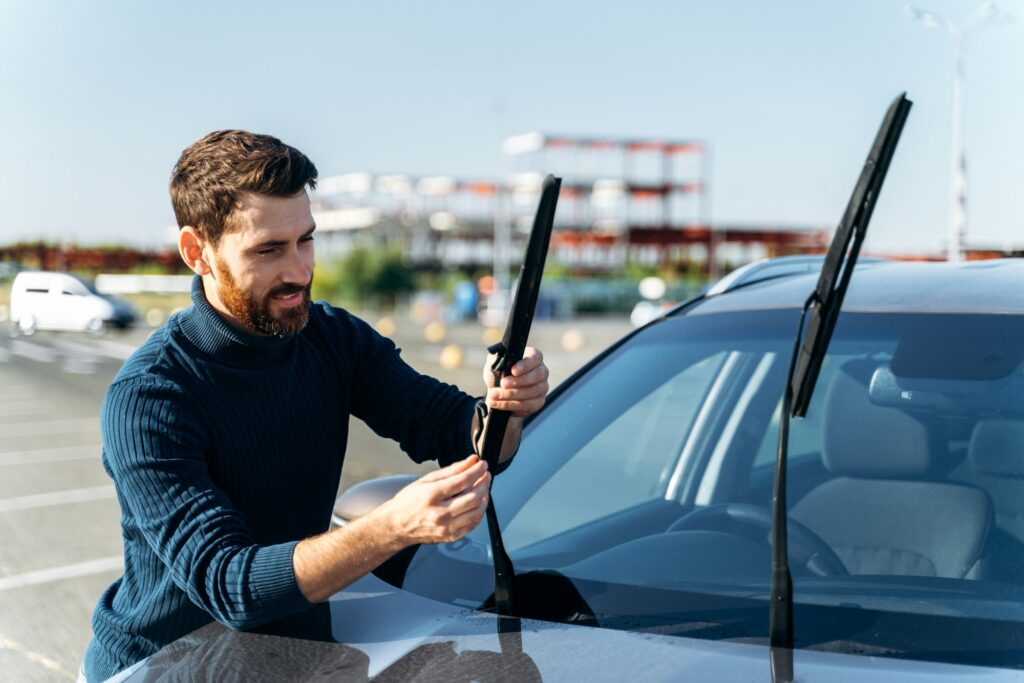 Male auto owner checking windshield wiper at the street